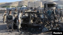 Security forces inspect a damaged car that was used during a suicide bomb attack outside the US consulate in Herat on September 13.