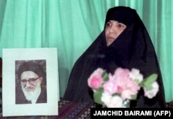 در کنار تصویری از پدرش در یک نشست خبری در تهران برای اعلام تمایل به نامزدی در انتخابات ریاست جمهوری ۷۶