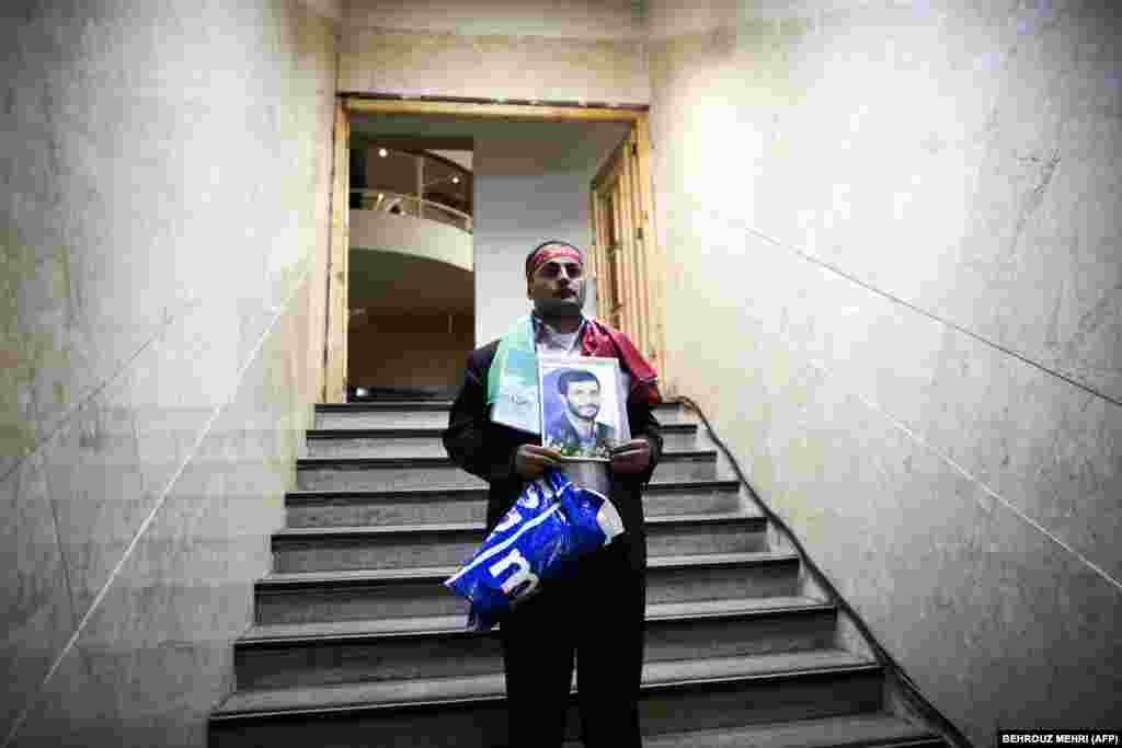 Rassoul Allahyari holds a portrait of Iranian President Mahmud Ahmadinejad as he arrives to register his candidacy for the upcoming presidential election at the Interior Ministry in Tehran. (AFP/Andrey Smirnov)