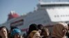 Refugee and migrant women line up as they wait to receive food distributed by Greek Red Cross at the port of Piraeus, near Athens, March 2, 2016. 