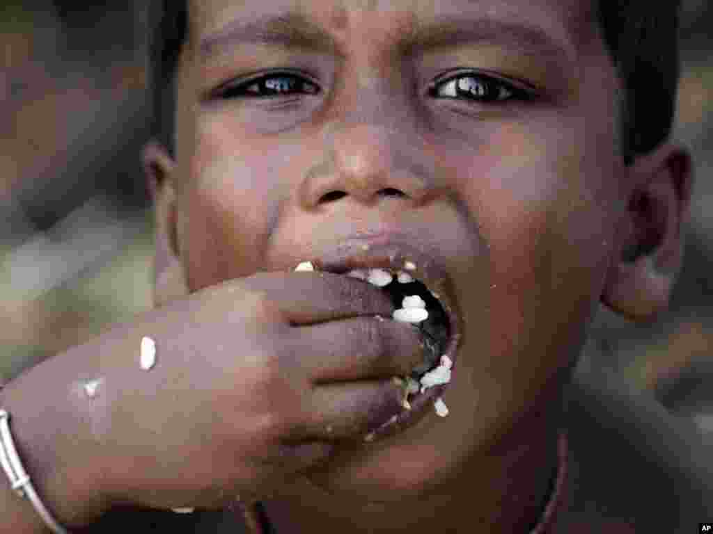 A child eats a meal distributed at a roadside relief camp for flood victims near Jajpur, India. (AP photo/Bikas Das)