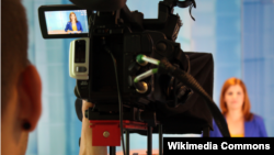 A woman stands in front of a camera in a studio. Illustrative. 