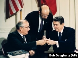 Američki predsjednik Ronald Raegan (desno) i sovjetski lider Mihail Gorbačov razmjenjuju olovke na ceremoniji potpisivanja Ugovora o zabrani posjedovanja nuklearnog oružja srednjeg dometa (INF) u Washingtonu 1987. godine.