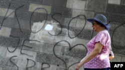 A woman in Belgrade walks past graffiti reading "Kosovo is the heart of Serbia."