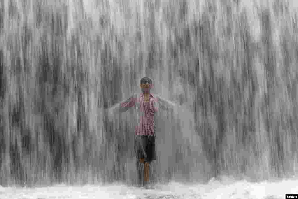 A boy stands under an overflowing dam along the Powai lake after heavy rains in Mumbai. (Reuters/Shailesh Andrade)