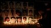 A man places a rose after lighting candles in front of portraits of the victims of the Taliban attack on the Army Public School in Peshawar, during a candlelight vigil in Lahore in this December 19, 2014 file photo.