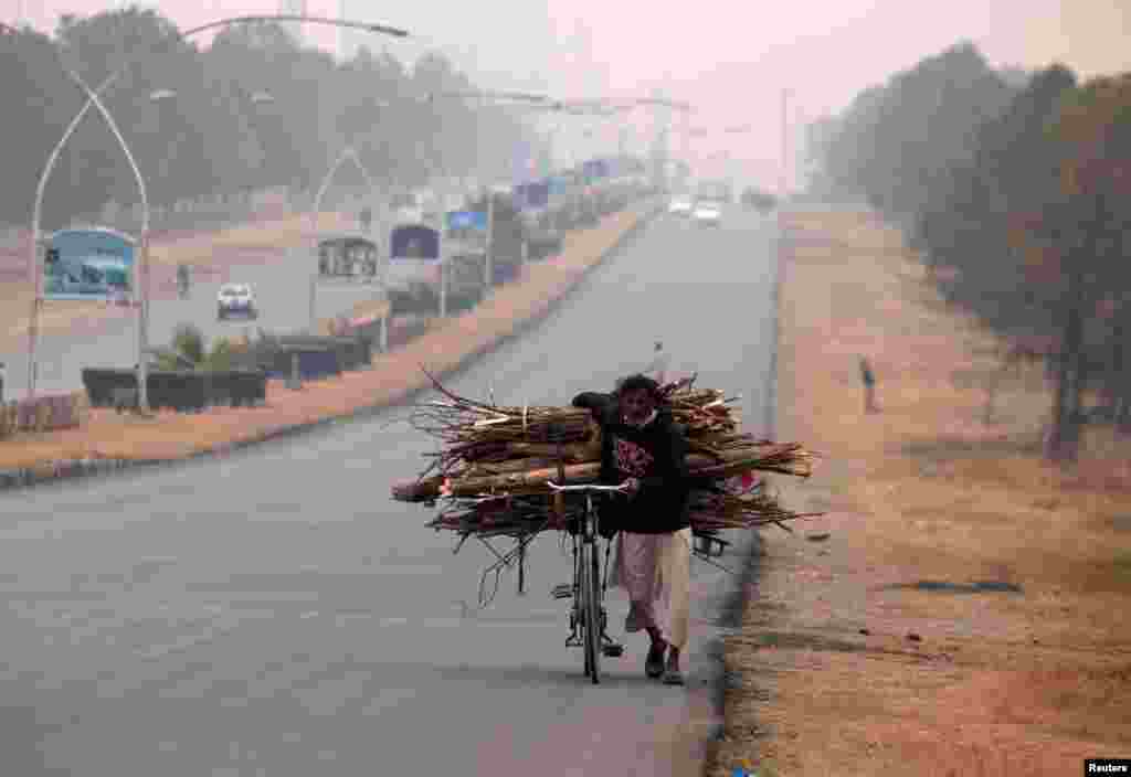 A man pushes a bicycle loaded with tree branches to be used for heating and cooking on a road in Islamabad, Pakistan. (Reuters/Faisal Mahmood&nbsp;)