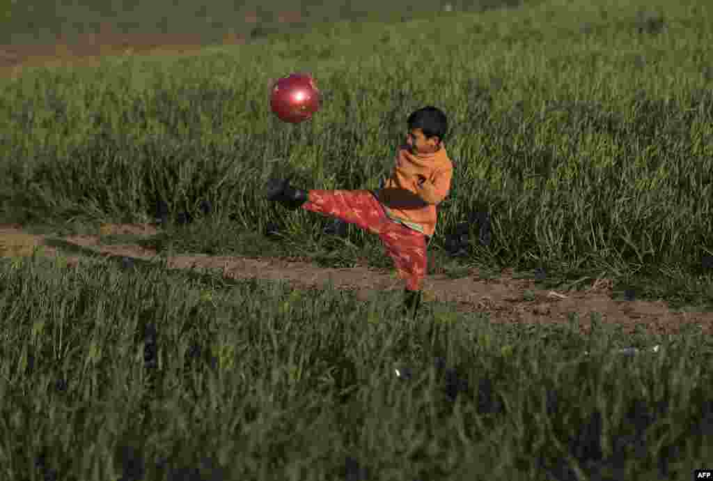 A boy plays with a ball at a makeshift camp for migrants and refugees at the Greek-Macedonian border near the village of Idomeni. (AFP/Joe Klamar)