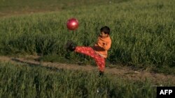 Greece -- A boy plays with a ball at a makeshift camp for migrants and refugees at the Greek-Macedonian border near the village of Idomeni, April 26, 2016
