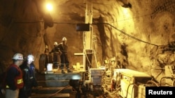 Workers stand beside machinery in a tunnel in the Kumtor mine.