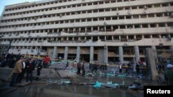 Police officers and others gather in front of the damaged Cairo Security Directorate, which includes police and state security, after a bomb attack on January 24.