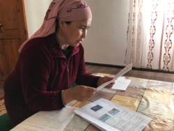 Жительница села Амангельды изучает домашние задания, которые ее дети получили почтой.