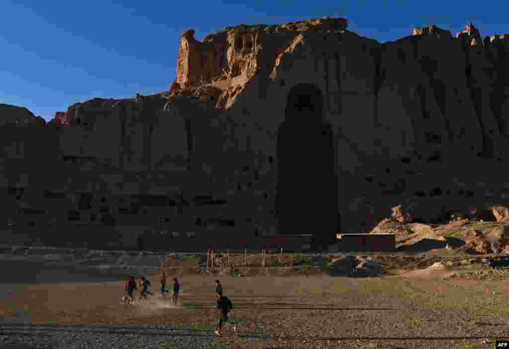 Hazara children play football near the site of the ancient Buddha statues destroyed by the Taliban.