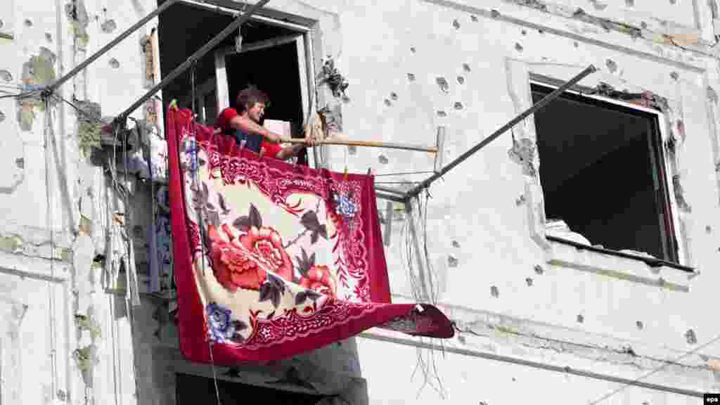 Женщина вывешивает ковер, вернувшись в свой разбомбленный дом в Цхинвали, столицу Южной Осетии. 23 августа, через неделю после окончания боев