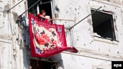 A woman dries a carpet after returning to her bullet-riddled home in Tskhinvali in August 2008.