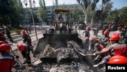 Metinvest workers remove barricades and debris in front of the City Hall in Mariupol