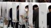 A woman leaves a voting booth to cast her ballot for the parliamentary elections at a polling station in Seoul on April 10.