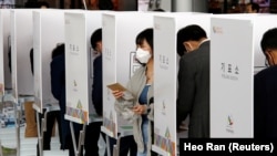 A woman leaves a voting booth to cast her ballot for the parliamentary elections at a polling station in Seoul on April 10.