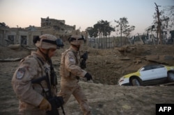 Croatian soldiers from the NATO coalition walk past a crater from a bomb blast as they inspect the site of an attack targeting the German Consulate in Mazar-e Sharif on November 11.