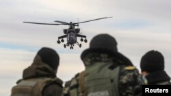 A Russian army chopper patrols the area as Ukrainian servicemen guard a checkpoint near the village of Strelkovo in the Kherson region adjacent to Crimea. Ironically many of the engines used by Russia's military helicopters are made in Ukraine. 