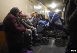 Locals sit in the basement of a police station as they seek shelter during a fire at an ammunition depot near Svatove.