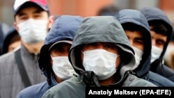 Migrant workers wearing protective face masks line up outside a migration control center to prolong their stay in Russia amid the ongoing coronavirus pandemic in St. Petersburg on April 3.