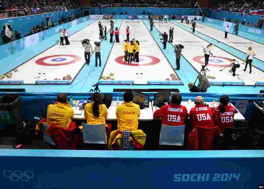 Coaches and team members of China and the United States watch their round-robin match in the curling competition in the Ice Cube Curling Center.