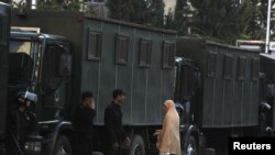 A woman asks riot police for directions as they block the road while standing guard near the Orthodox church where New Year's bomb attacks took place in Alexandria, Egypt.