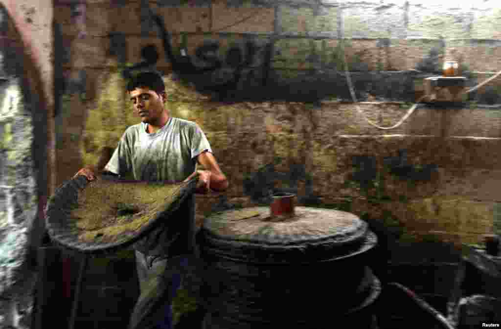 A Palestinian man carries a sheet of ground olives to be made into oil at an olive press in Gaza City. (Reuters/Mohammed Salem)