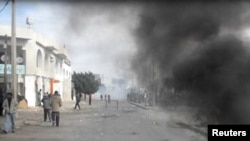 Smoke fills a street in Rgeb, Tunisia, where funeral processions were being held on January 10 for people shot in recent clashes with police.