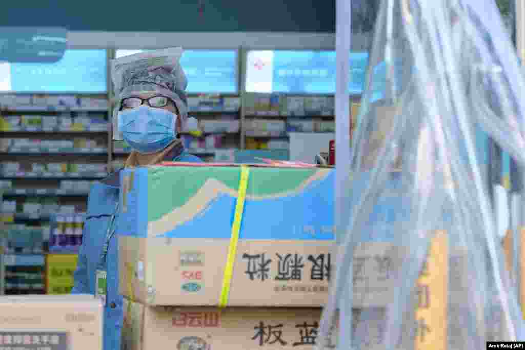 CHINA -- A clerk wearing a face mask and a plastic bag stands in a pharmacy in Wuhan in central China's Hubei Province, January 31, 2020