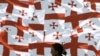 A woman walks past a wall decorated with Georgia's national flags in the center of Tbilisi. 