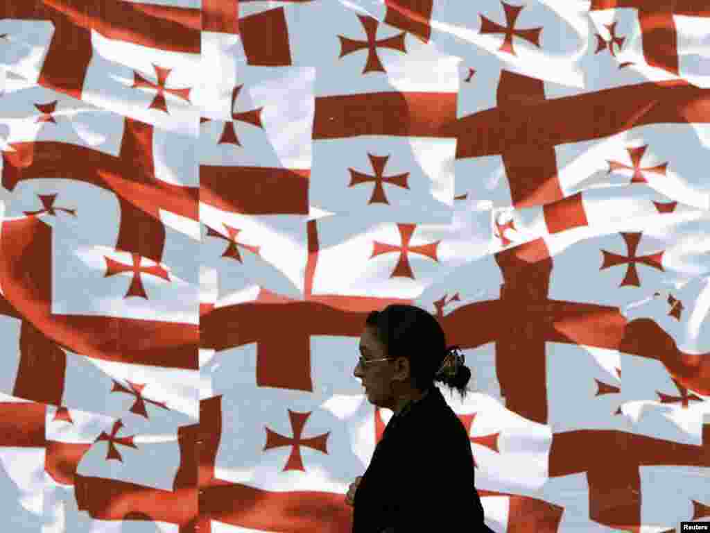 A woman walks past a wall decorated with Georgian national flags in central Tbilisi ahead of Georgia's Independence Day on May 26. Photo by David Mdzinarishvili for Reuters