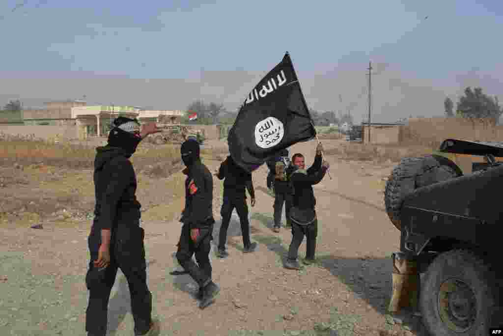 Iraqi government forces celebrate while holding an Islamic Sate flag after they claimed to have gained complete control of Diyala Province, northeast of Baghdad. (AFP/Younis al-Bayati)