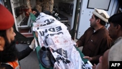 Pakistani men carry the body of a student outside a school attacked by Taliban gunmen in Peshawar on December 16.