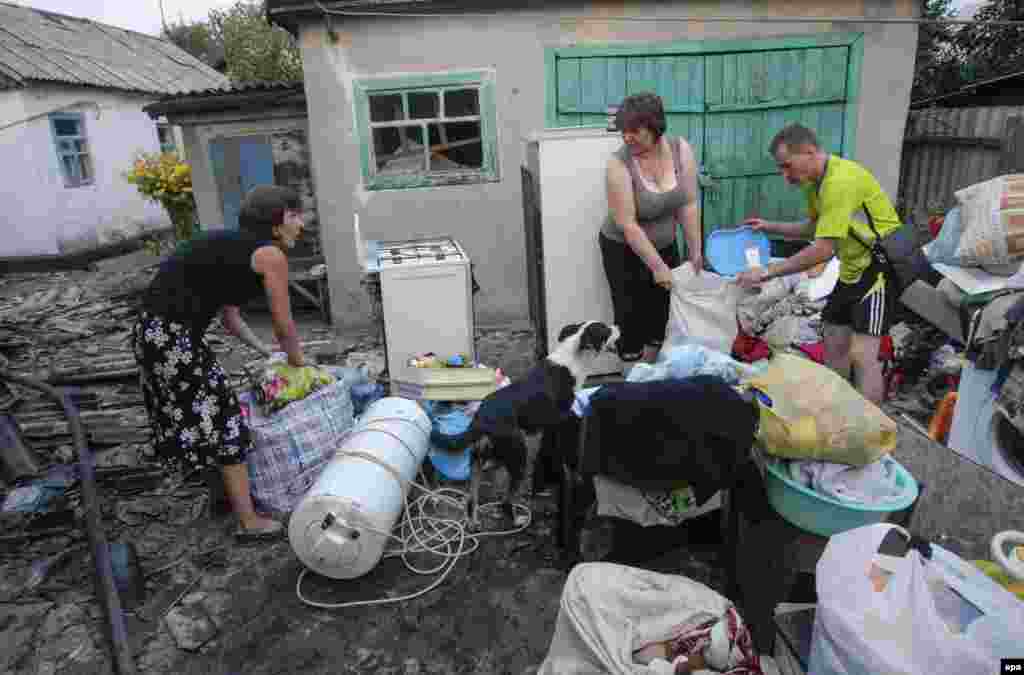Родина перекладає рештки майна, яке вціліло після пожежі внаслідок обстрілу в Донецьку, 12 серпня 2015 року