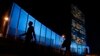 Pedestrians walk by United Nations Headquarters, lit up in blue light, a day in advance of the 70th Anniversary of the U.N., Friday, Oct. 23, 2015, in New York. Around 200 other buildings and structures in 60 other countries were also lit in blue to comme