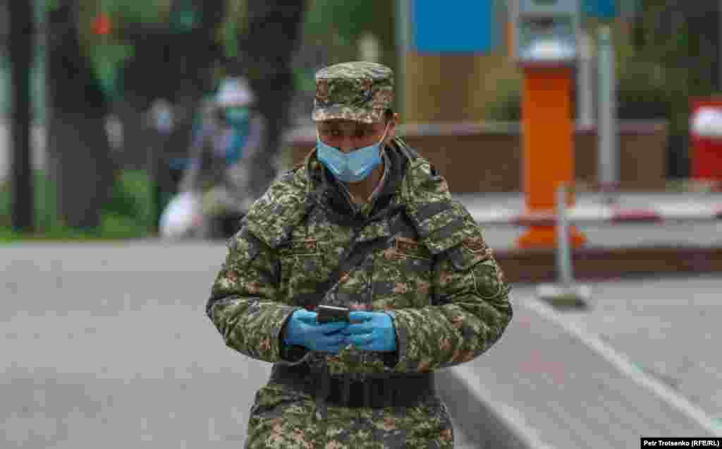 Военный в маске и перчатках идет по улице.