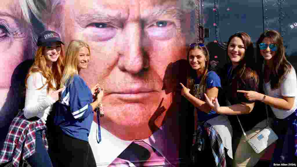 Студенты позируют для фотографии на фоне изображения Дональда Трампа