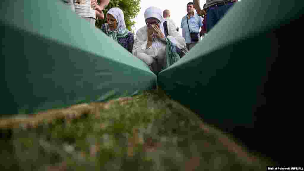 People mourn near coffins of their relatives, which are lined up for burial in Potocari near Srebrenica, July 10, 2017.