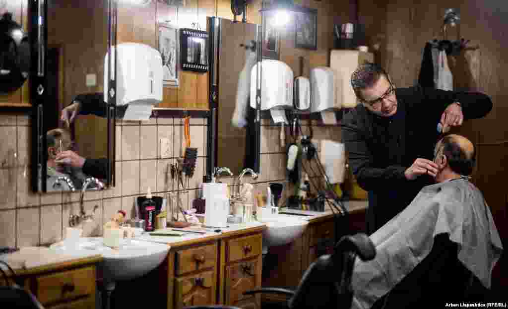 A barber clipping into the evening in Pristina. (Photo by Arben Llapashtica)