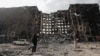 Un locuitor din Mariupol în fața unui bloc de apartamente distrus în timpul conflictului dintre Ucraina și Rusia, în orașul asediat din sudul Ucrainei, 25 martie 2022. 