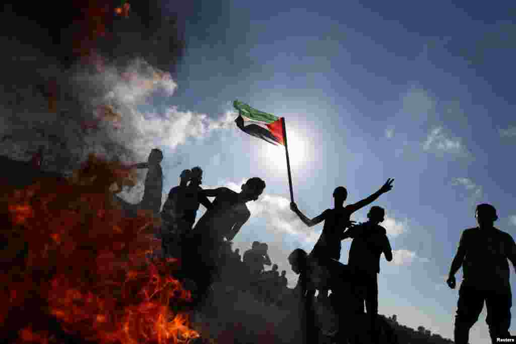 A Palestinian protester gestures as others hurl stones at Israeli troops during clashes near the border between Israel and central Gaza Strip. (Reuters/Ibraheem Abu Mustafa)