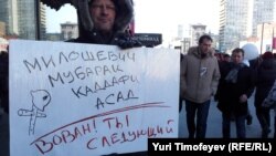 Участник акции протеста в Москве держит плакат с надписью "Милошевич. Мубарак. Каддафи. Асад. Вован, ты следующий!" Москва, 10 марта 2012 года.