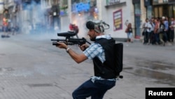 A plainclothes police officer fires plastic paintball gun pellets to disperse protesters in central Istanbul earlier this month. 