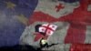 A man with a Georgian flag sits in front of a projection of the Georgian and European flags during celebrations for the signing of an Association Agreement with the European Union in Tbilisi on June 27.