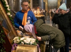 Вірянка РПЦ цілує мощі св. Івана Хрестителя, завдання волонтера – протирати скло після кожного поцілунку. Санкт-Петербург, 15 березня 2020 року