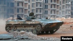 A fighter from Jabhat Fateh al-Sham, formerly the Al-Nusra Front, drives a tank through apartment blocks in southwestern Aleppo on August 5. The group used suicide sappers and tunnel bombs to break open the Syrian Army's battle lines and main defenses.