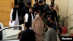 Policemen escort Sharbat Gula (C), as she leaves after appearing before a court in Peshawar Pakistan on November 4. The green-eyed Afghan woman who became a symbol of her country's wars 30 years ago when her photo as a girl appeared on the cover of National Geographic magazine.