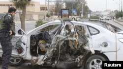 Сотрудник иракских служб безопасности осматривает взорвавшийся автомобиль.
